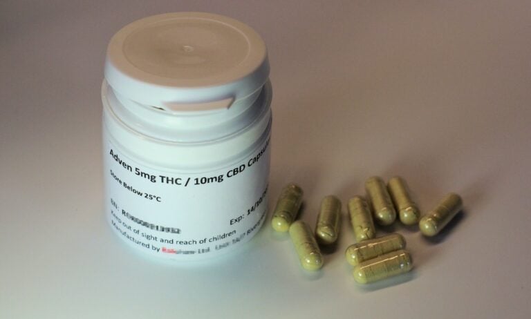white plastic bottle with brown tablets of THC