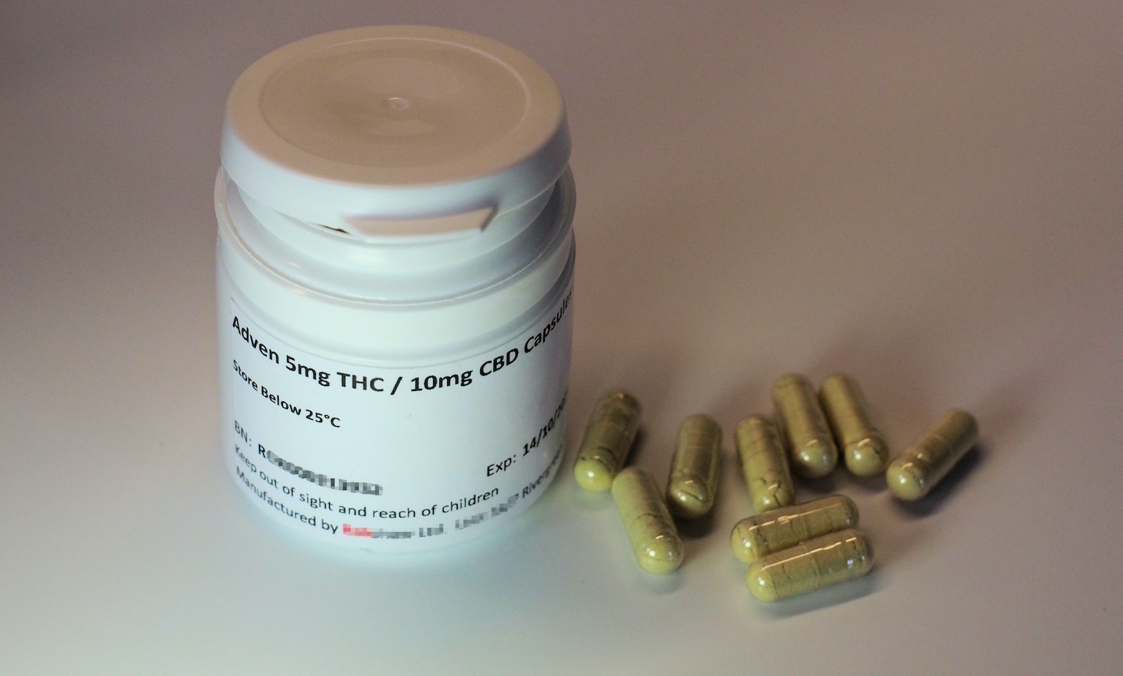 white plastic bottle with brown tablets of THC