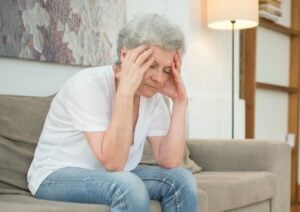 Agitated Woman in a White Shirt and Denim Pants Sitting on a Couch