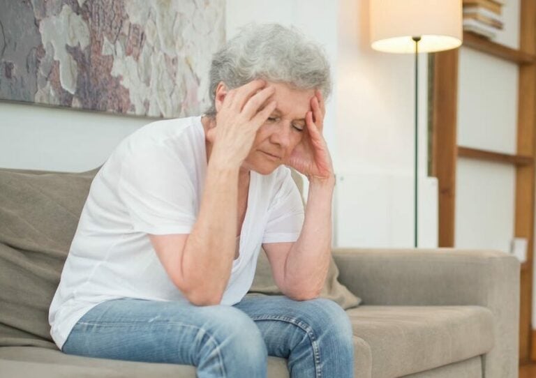 Agitated Woman in a White Shirt and Denim Pants Sitting on a Couch