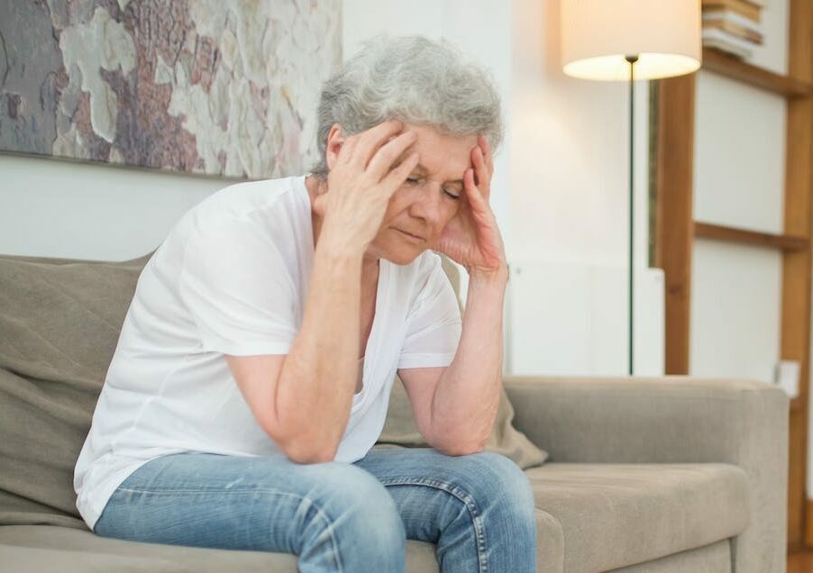 Agitated Woman in a White Shirt and Denim Pants Sitting on a Couch