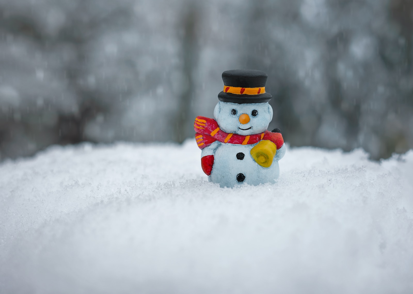 snowman in red scarf and black hat, holding a gift