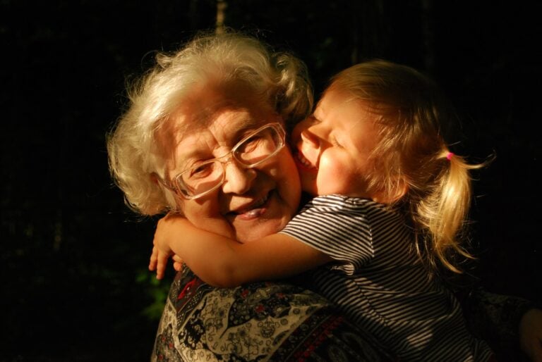 Grandmother in black and white striped shirt hugging girl in black and white striped shirt