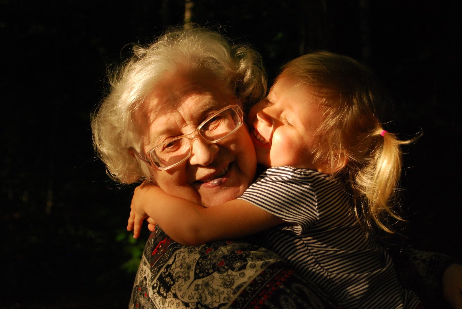 Grandmother in black and white striped shirt hugging girl in black and white striped shirt