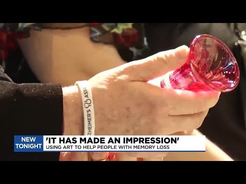 A person with Alzheimer's blowing glass in an art workshop