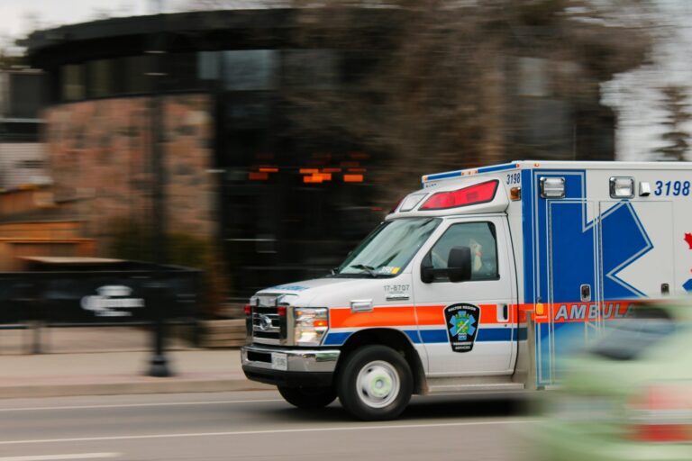 white and blue ambulance van traveling fast on road
