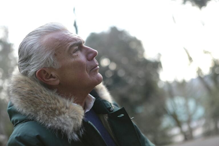 Profile of a senior man in a winter coat enjoying a peaceful outdoor moment.
