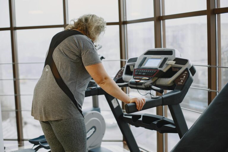 A senior woman using a treadmill at the gym, focusing on fitness and wellbeing.