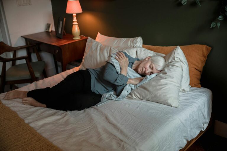 Senior woman sleeping peacefully in a cozy bedroom with warm lighting.