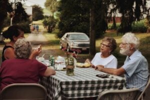 man in white crew neck t-shirt sitting on chair in front of table with food